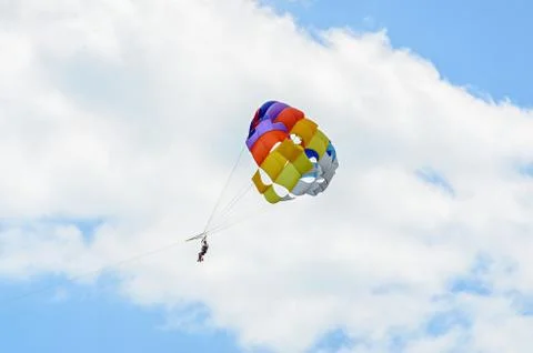 Colored parasail wing in the blue clouds sky, Parasailing also known as paras Stock Photos