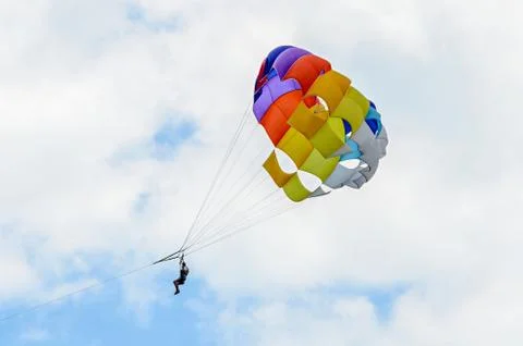 Colored parasail wing in the blue clouds sky, Parasailing also known as paras Fotos Stock