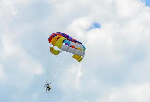 Colored parasail wing in the blue clouds sky, Parasailing also known as paras Fotos de archivo