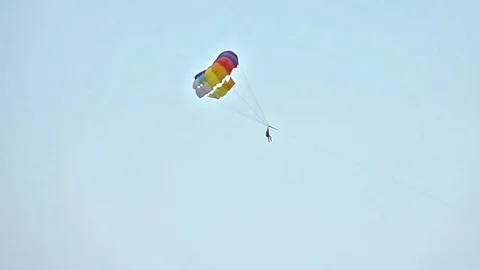 Colored parasail wing flying in the blue cloudy sky, Parasailing also known a Stock Footage 81068937