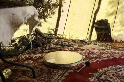 On the colored patterned carpets in the tent lies a round golden tambourine. Stock Photos
