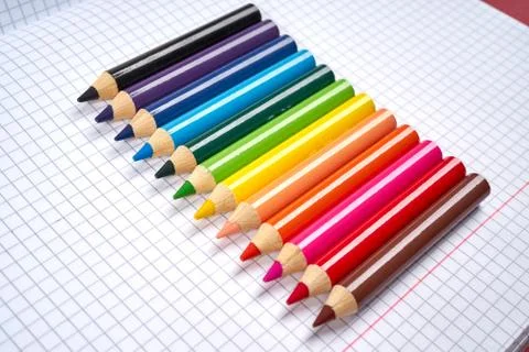 Colored pencil crayons on an open checkered notebook Stock Photos