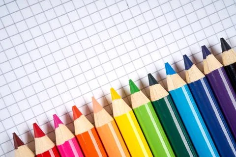 Colored pencil crayons on an open checkered notebook Stock Photos