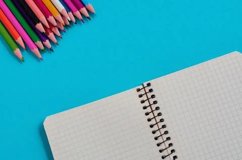 Colored pencils and notebook on a blue background. Copy space. Stock Photos