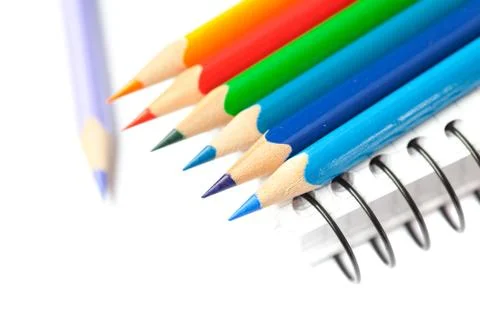 Colored pencils and a notebook isolated on white Stock Photos