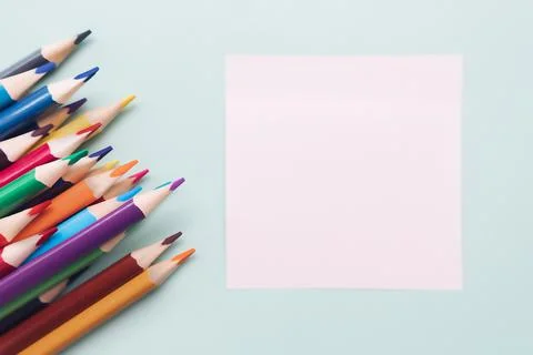 Colored pencils and a sheet for notes lie on a blue background. Top view Foto stock