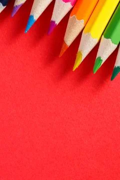 Colored pencils angle. Many different colored pencils on red background Stock Photos