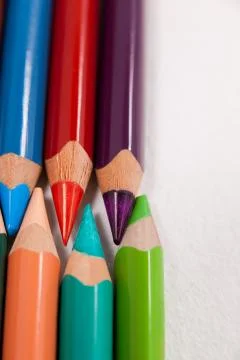 Colored pencils arranged in interlock pattern on white background Stock Photos