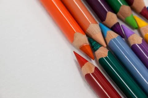 Colored pencils arranged in interlock pattern on white background Stock Photos