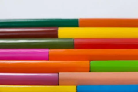 Colored pencils arranged in interlock pattern on white background Foto stock
