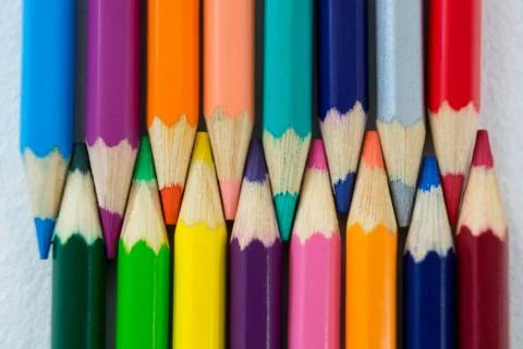 Colored pencils arranged in interlock pattern on white background Foto stock