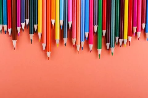 Colored pencils, on coral background, pattern, copy space. Stock Photos
