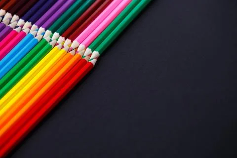 Colored pencils on dark background lying in opposite corners Stock Photos