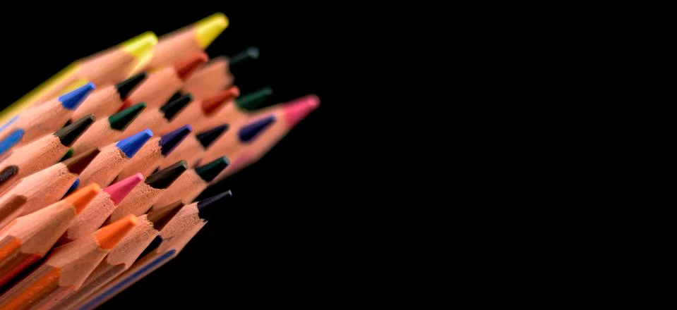 Colored pencils hovering from the left side of the image on black background Stock Photos