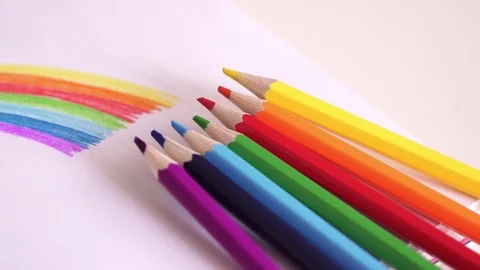 Colored pencils lie at the drawing of a rainbow on a table. Bright colourful Stock Footage 88292194