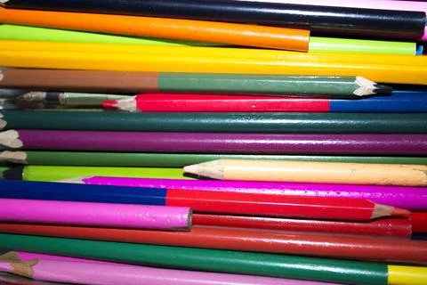 Colored pencils lying in irregular row on white background Stock Photos