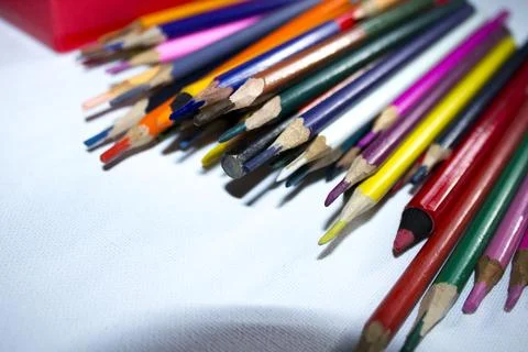 Colored pencils lying in irregular row on white background Stock Photos
