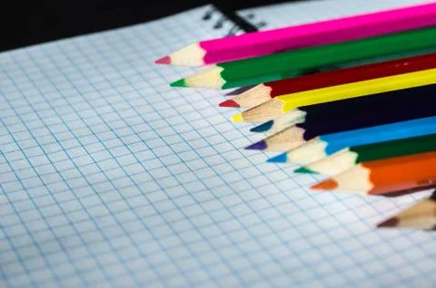 Colored pencils lying on an open notebook Stock Photos