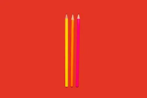 Colored pencils lying on a red background Stock Photos