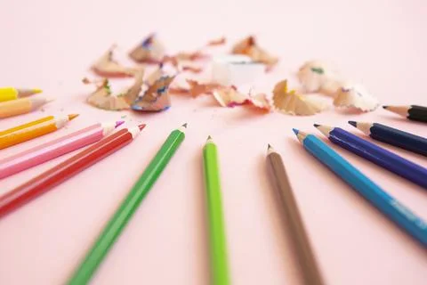 Colored pencils next to sharpener on light pink background Stock Photos