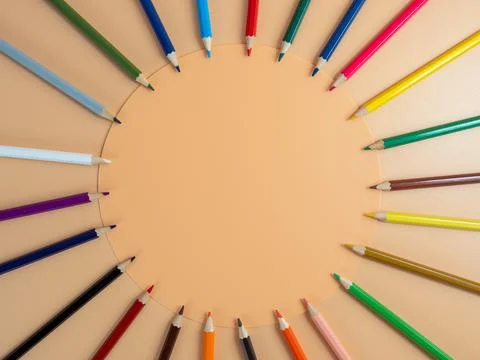 Colored pencils on an orange background. Stock Photos