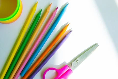 Colored pencils, scissors and container are located on a white background, top Stock Photos