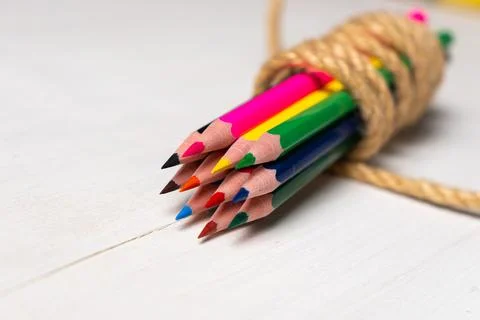 Colored pencils tied with a string on a white table Stock Photos