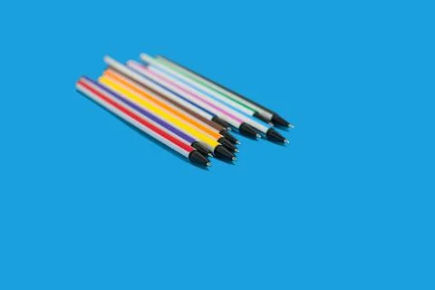 Colored pens lying on a blue background Stock Photos