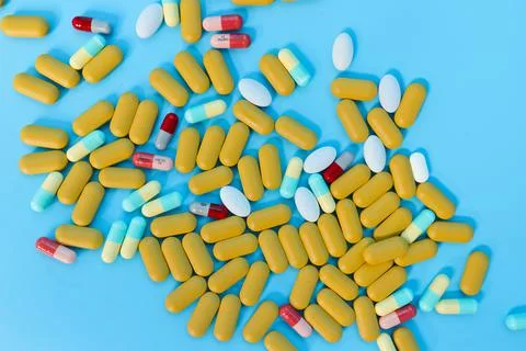 Colored pills on blue background. Stock Photos