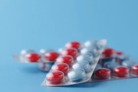 Colored pills in cluster on blue background Stock Photos