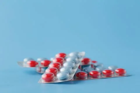 Colored pills in cluster on blue background Stock Photos