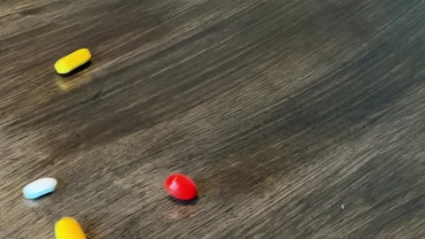 Colored pills falling on the table Видео 176620038