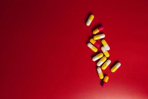 Colored pills on red background Fotos de archivo