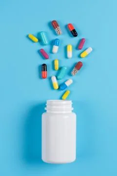 Colored pills, tablets and white bottle on blue background Stock-Fotos