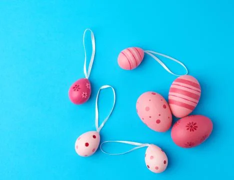 Colored pink easter eggs on a blue background, close up Stock Photos