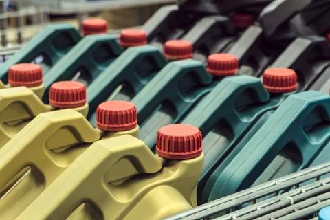 Colored plastic cans with engine oil. Rows of canisters placed on a pallet. Stock Photos
