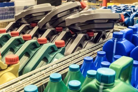 Colored plastic cans with engine oil. Canisters placed on a pallet. Stock Photos