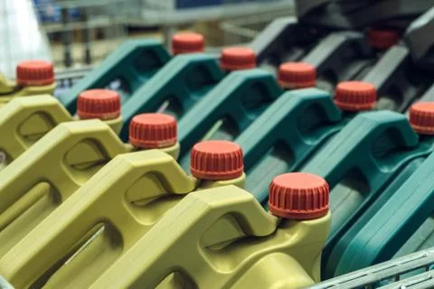 Colored plastic cans with engine oil. Rows of canisters placed on a pallet. Stock Photos