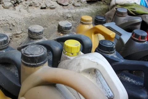 Colored plastic cans with engine oil. Rows of canisters placed on the ground Stock Photos