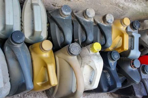 Colored plastic cans with engine oil. Rows of canisters placed on the ground Stock Photos