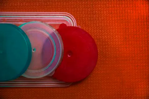 Colored plastic lids on orange background Stock Photos