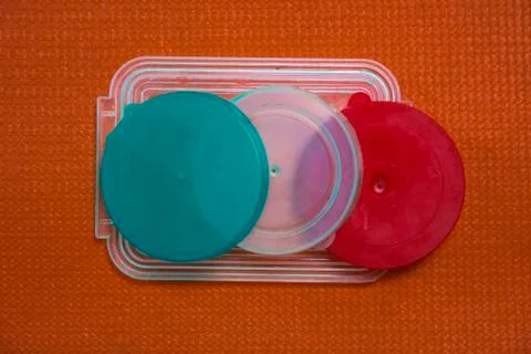 Colored plastic lids on orange background Stock Photos