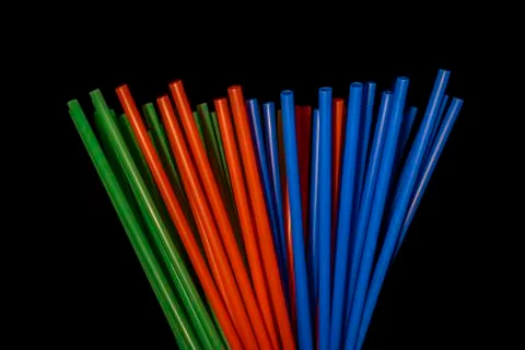 Colored plastic straws on black background and low light. Stock Photos