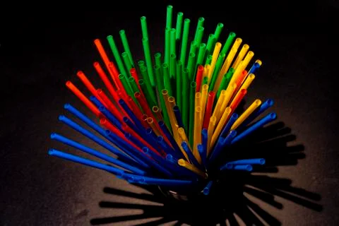 Colored plastic straws on black background and low light. Stock Photos