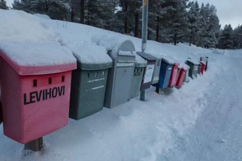 Colored post boxes line covered by snow in Levi, Finland Stock Photos