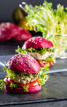 Colored purple beetroot buns and chicken burgers. Stock Photos