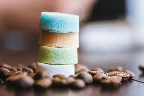 Colored round sugar cubes among coffee beans Stock Photos