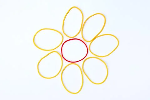 Colored rubber bands folded in the shape of a flower on a white surface Stock Photos