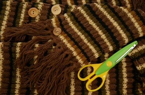 Colored scissors on knitted background with stripes. Stock Photos