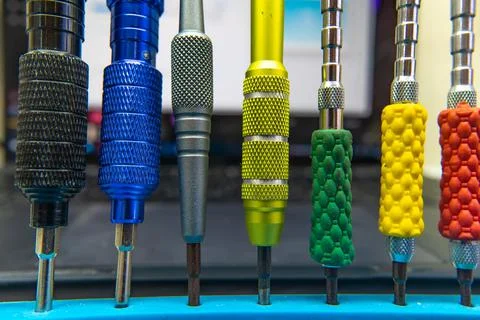 Colored screwdrivers stand in a row on the workshop desktop. Stock Photos